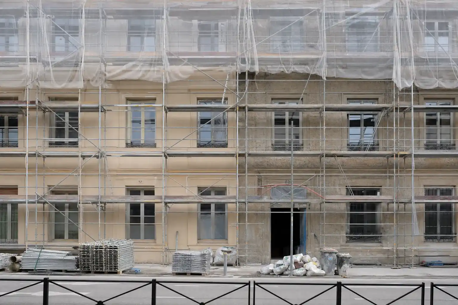 Façade d’immeuble lyonnais en cours de ravalement sous échafaudage, enduit refait sur la moitié gauche